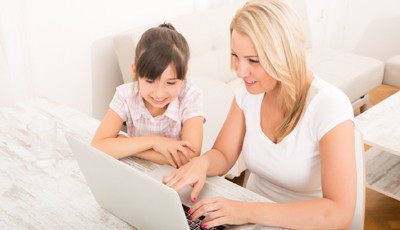 A mother with her daughter looking at a Laptop at home.